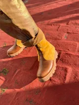 Botas de caña baja combinadas en cuero marrón y corderito en tono mostaza, con suela track gruesa y cierre lateral.