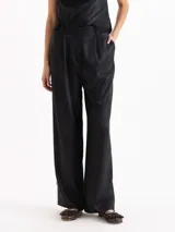 Pantalón palazzo de tiro alto color negro, confeccionado en twill de viscosa con caída fluida. Cuenta con cintura clásica con presillas, pinzas frontales, bolsillos laterales y una delicada aplicación de puntilla de encaje a lo largo de ambos laterales.