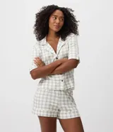 Pijama corto de dos piezas confeccionado en viscolycra con estampado de cuadros. Compuesto por una camisa de mangas cortas con cuello de solapa y cierre frontal de botones, y un short con cintura elastizada.