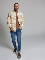 Sobrecamisa de manga larga con diseño a cuadros en tonos beige y marrón. Presenta cuello clásico, cierre frontal con botones y dos bolsillos en el pecho.