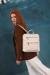 Mochila mediana de cuero sintético con textura rugosa, cuenta con dos compartimentos frontales con cierre, asa superior y correas ajustables.