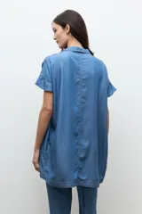 Túnica corta de lyocell color azul jean, con cuello en V, cuello camisero sutil, mangas cortas y costuras con pespuntes visibles en el frente.
