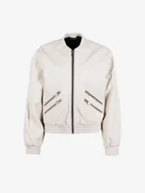 Chaqueta bomber color blanco hueso de corte oversize, con cierre frontal y bolsillos laterales con doble cremallera.