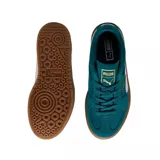 Championes Puma modelo Palermo Elevata, de diseño urbano con plataforma. Presenta una capellada de gamuza negra con la icónica franja lateral en cuero blanco y detalles dorados en la lengüeta y el lateral. Cuenta con una suela de plataforma de goma color caramelo.