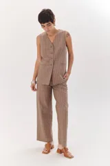 Chaleco largo color blanco con rayas verticales finas color beige, con cuello en V y cierre frontal con botones marrones. Incluye pañuelo al cuello con estampado de lunares y rayas.