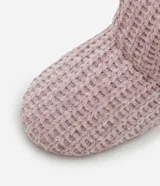 Pantufla tipo bota en color rosado, con superficie externa de tejido texturizado y borde superior e interior forrado en peluche blanco.