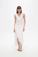 Musculosa de algodón sin mangas, de corte cruzado con cuello en V y diseño holgado, color blanco con estampado de lunares bordó y lazo lateral para ajustar.