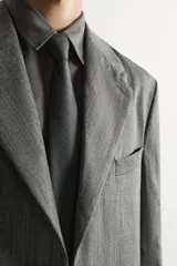 Blazer de corte relaxed fit de Zara, confeccionado en 100% lana color gris. Cuenta con cuello de solapas de muesca, manga larga, bolsillos de parche en la cadera, bolsillo de vivo en el pecho y cierre frontal con un botón.
