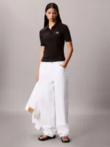 Chomba de Calvin Klein confeccionada en tejido canalé de algodón con elastano. Presenta cuello tipo polo con cartera de dos botones, mangas cortas y un ajuste estructurado. Incluye una pequeña insignia de la marca en el dobladillo inferior.