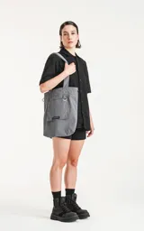 Bolso tipo tote bag de microfibra técnica color gris, con cordón ajustable con tanca. Posee un bolsillo externo con velcro y un bolsillo interno con cierre.