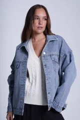 Campera clásica de jean celeste con cuello camisero, bolsillos frontales con solapa y cierre con botones metálicos. Presenta detalles de pequeños brillos blancos dispersos en la parte delantera y las mangas.