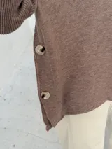 Polerón de punto color visón con cuello alto holgado, mangas largas con puños acanalados y diseño de corte amplio.