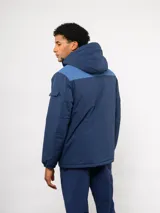 Parka de abrigo Umbro del Club Nacional de Football, con diseño de bloques de color en azul, rojo y blanco. Cuenta con capucha, cierre frontal, bolsillos frontales y el escudo del club bordado en el pecho.