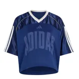 Remera de mujer Adidas W Sta Seas Tee, de color azul marino con diseño estilo jersey deportivo, cuello en V y mangas cortas con las clásicas franjas de la marca. Presenta el logotipo y la inscripción de Adidas estampados en el frente.