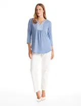Blusa de modal texturizado en color azul, con cuello a la base y escote en V. Presenta un panel frontal decorado con apliques circulares nacarados y mangas tres cuartos.