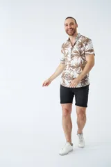 Camisa de manga corta con estampado botánico de hojas en tonos azul y blanco. Presenta cuello clásico, cierre frontal abotonado y corte slim.