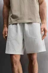 Pantalones cortos tipo jogger de corte relajado confeccionados en tejido de algodón. Presentan cintura elástica con cordón interior, bolsillos frontales en la cadera y un bolsillo trasero de plastrón.
