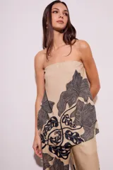 Top strapless color beige con estampado de hojas negras.