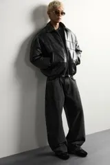 Cazadora acolchada relaxed fit de efecto piel en color negro, con cuello camisero, cierre frontal de cremallera metálica, bolsillos frontales de vivo y puños elásticos.