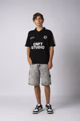 Remera tipo chomba tejida de algodón color negro, con cuello en V y mangas cortas. Presenta detalles de rayas blancas en cuello y mangas, y estampados con logos en el frente.