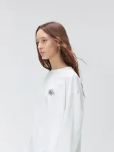 Remera oversize de manga larga color naranja con efecto gastado, cuello redondo y gráfico estampado en la espalda.