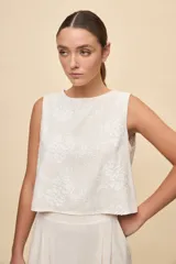 Top sin mangas color blanco con escote redondo, calce amplio y diseño con bordado floral en relieve.