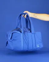 Bolso tipo tote color beige con diseño acolchado y doble asa de hombro.