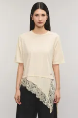 Remera oversize de jersey de algodón color blanco, con escote redondo, mangas cortas y bajo asimétrico con detalle de encaje y puntilla.