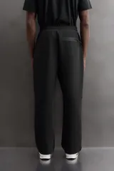 Pantalón jogger relaxed fit Zara Athleticz de tejido técnico compacto elástico con mezcla de algodón. Presenta cintura elástica ajustable con cordón, bolsillos laterales en la cadera, bolsillo trasero con cierre de cremallera, bajo ajustable con elástico y detalle de logo estampado en la pernera.
