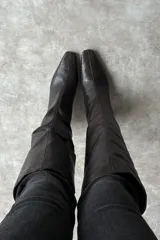Bota bucanera negra de cuero con estampado animal print tipo serpiente, diseño de caña alta y taco fino bajo con punta afilada.