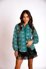 Camisa verde esmeralda con estampado de flores blancas, cuello clásico, mangas largas abullonadas y cierre frontal con botones.