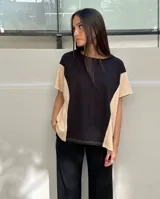 Remera de corte holgado confeccionada en viscocreppe, con diseño bicolor que combina un panel central negro con laterales en color beige. Presenta cuello redondo, mangas cortas y costuras con pespuntes visibles.