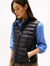 Chaleco negro de nailon con relleno de plumón, cuello mao, cierre de cremallera, bolsillos laterales con cremallera y logo de Tommy Hilfiger estampado en el pecho.