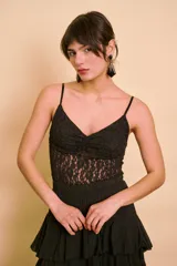 Musculosa negra confeccionada en encaje con diseño floral, tirantes finos ajustables y escote en V con fruncido central.