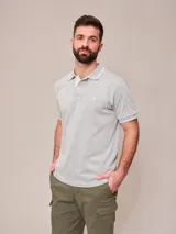 Chomba gris melange de manga corta, con cuello polo y ribetes blancos en el cuello y los puños. Cuenta con cierre frontal parcial de botones y pequeño bordado al tono en el pecho.