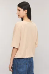 Remera oversize color blanco, confeccionada en jersey Pima flamé de algodón. Cuenta con escote en V, mangas cortas con detalle de bordado en la manga y cintura con elástico que genera un efecto balloon.