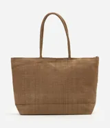 Cartera amplia confeccionada en fibra de papel, de color beige, con asas de hombro, cierre superior y detalle metálico dorado claro en el frente.