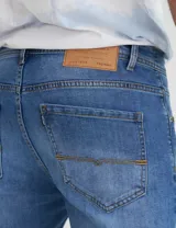 Pantalón de jean celeste de corte slim fit con efecto lavado y roturas sutiles.