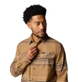 Camisa de manga larga Columbia, confeccionada en franela de algodón con un toque de elastano para mayor comodidad. Presenta un diseño de rayas horizontales en tonos tierra, cuello clásico, cierre frontal con botones y dos bolsillos en el pecho con solapa y botón.