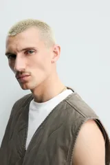 Chaleco acolchado de algodón color verde militar, de corte relaxed fit, con cuello en V, cierre frontal con cremallera y bolsillos de parche en la cadera. Presenta diseño acolchado con pespuntes ondulados y efecto lavado.