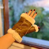 Mitones de cuero napa y lana color marrón, sin dedos, con detalles de corderito sintético blanco en los bordes y el pulgar. Incluye una etiqueta de cuero con la marca grabada.