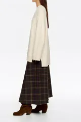 Sweater de punto negro con efecto tweed o neps en color dorado/amarillo claro, cuello alto tipo caja y mangas largas. Corte recto y holgado.