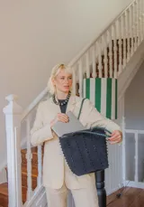 Cartera tipo tote de gamuza color marrón, con correas trenzadas y detalle de piedras naturales incrustadas en líneas verticales. Cuenta con cierre metálico y forro interior de tela.