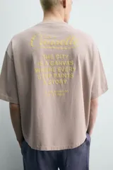 Camiseta boxy fit color gris topo, de cuello redondo y manga corta, con pequeño estampado frontal a contraste.