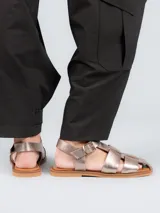 Sandalias tipo pescador con diseño de tiras anchas entrelazadas, confeccionadas en cuero color plateado. Presentan cierre mediante hebilla metálica lateral, plantilla de cuero y suela plana de goma.