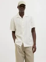 Camisa de manga corta color blanco con rayas verticales, cuello resort y cierre de botones.