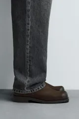 Bota de cuero color marrón oscuro con diseño de caña media, horma cuadrada y cierre lateral mediante cremallera. Cuenta con suela a contraste y un ligero tacón.