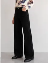 Pantalon de pana color negro, de tiro alto y corte wide leg. Presenta diseño clásico de cinco bolsillos, cierre frontal con botón y una caída amplia y recta.
