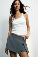 Falda pantalón de tiro medio color negro, con detalle de abertura en el delantero y cierre lateral con cremallera oculta.