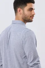 Camisa de lino a cuadros en tonos celeste y blanco, de manga larga, con cuello camisero, cierre frontal con botones y un bolsillo ojal en el pecho con detalle bordado.